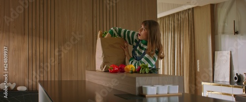 Foto Happy positive Caucasian female woman unpacking the paper bag with her delivery
