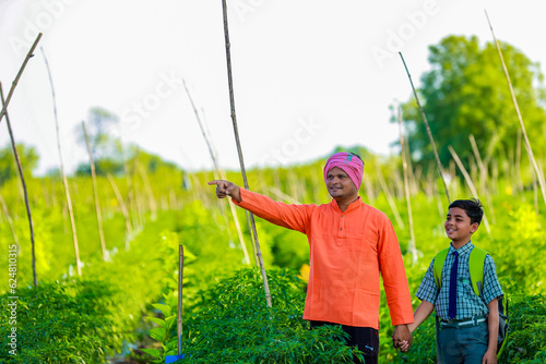 Cute indian farmer child in school uniform with his father at agriculture field