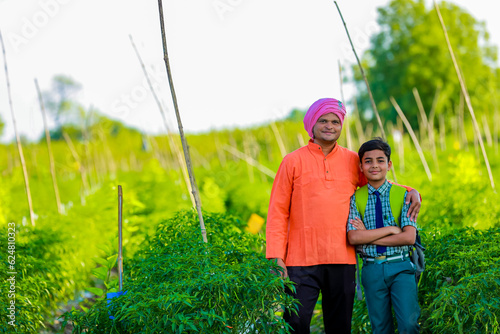 Cute indian farmer child in school uniform with his father at agriculture field