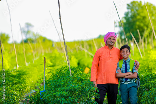 Cute indian farmer child in school uniform with his father at agriculture field