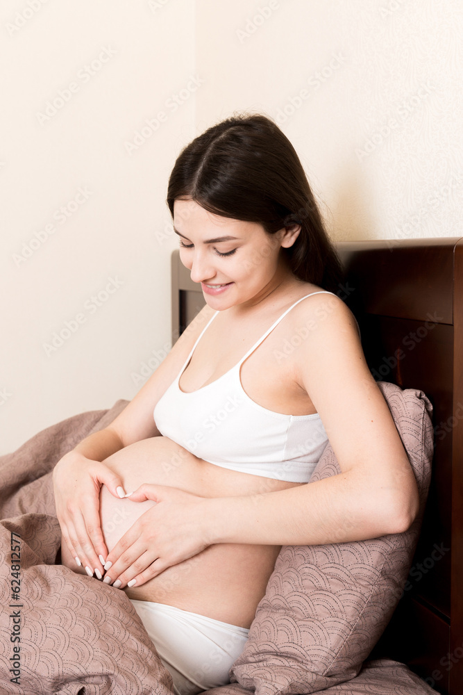 happy pregnant woman making heart in home on bed. Pregnancy, love and expectation concept happy pregnant woman making heart in home on bed. Pregnancy, love and expectation concept