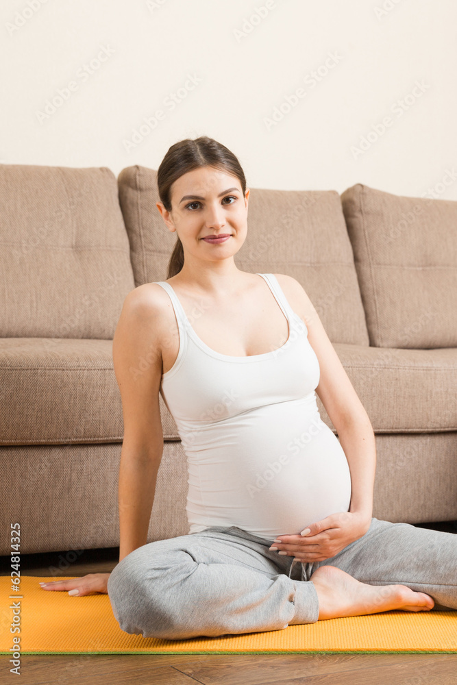 Portrait of young pregnant yoga model working at the home. Pregnancy Yoga and Fitness concept at coronavirus time