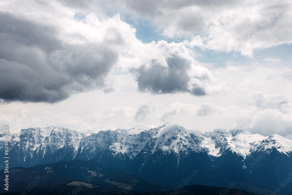 view over snow covered mountains on cloudy sky background.