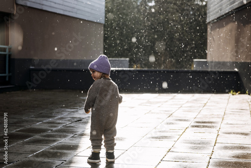 Child walking under the rain on a spring day. © Bostan Natalia