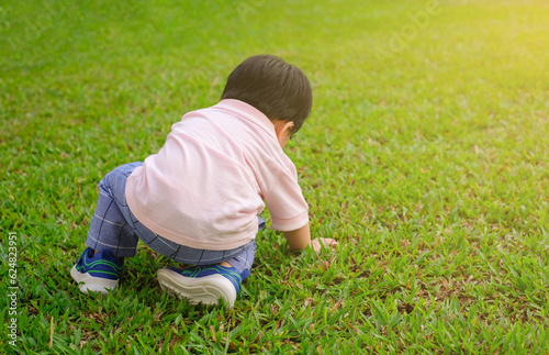 Close up of asian baby playing grass in the garden with sunset. Joyful and healthy child