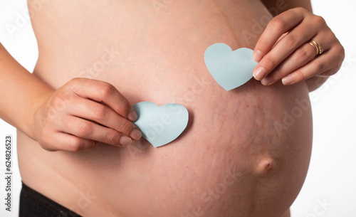 Two blue hearts on the background of the girl's pregnant belly. The concept of love for children and the birth of twin boys. Preparation for childbirth