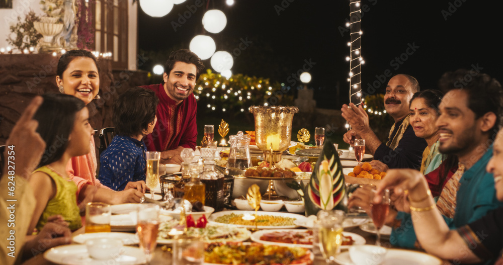 Big Indian Family Celebrating Diwali: Family Gathered Together on a Dinner Table in a Backyard Garden Full of Lights. Group of People Sharing Food, Laughs and Stories on a Hindu Holiday