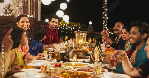 Big Indian Family Celebrating Diwali: Family Gathered Together on a Dinner Table in a Backyard Garden Full of Lights. Group of People Sharing Food, Laughs and Stories on a Hindu Holiday