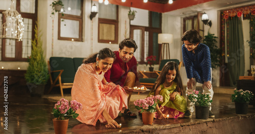 Portrait of an Indian Family Celebrating Divali by Putting Lamps in Their Backyard. Happy Young Parents and Their Exited Children Participating in Hindu Religious Festivities, Festival of Lights