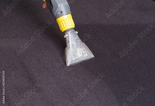 Dry cleaning of the black upholstery on the sofa with a special washing vacuum cleaner. Copy space for text