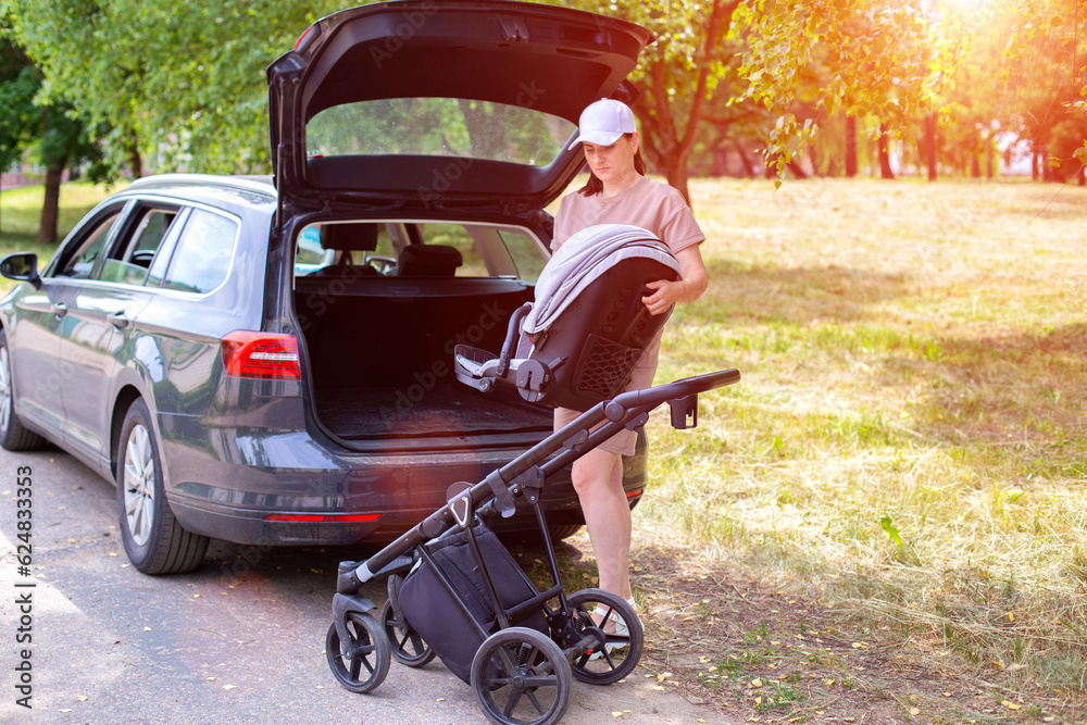 A beautiful girl puts a baby stroller into the open trunk of a car. Traveling in a family car. Copy space for text A beautiful girl puts a baby stroller into the open trunk of a car. Traveling in a family car. Copy space for text