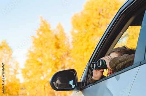 Fotografi Boy inside car watching birds through binoculars