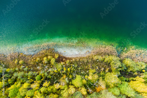 Aerial view of beautiful green waters of lake Gela. Birds eye view of scenic emerald lake surrounded by pine forests. Clouds reflecting in Gela lake, near Vilnius, Lithuania.