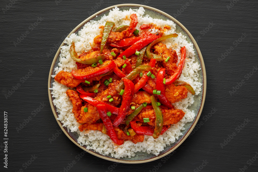 Homemade Simple Chili Chicken with White Rice on a Plate on a black background, top view. Flat lay, overhead, from above. Homemade Simple Chili Chicken with White Rice on a Plate on a black background, top view. Flat lay, overhead, from above.