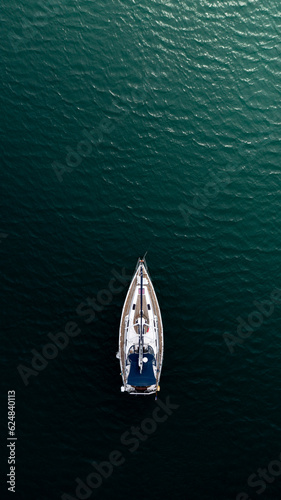 Fotografering Top down aerial view of a sail boat sailing towards the light