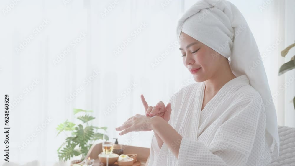 Young woman in nice bathrobe applying moisturizer on hands after taking shower. Young woman in nice bathrobe applying moisturizer on hands after taking shower.