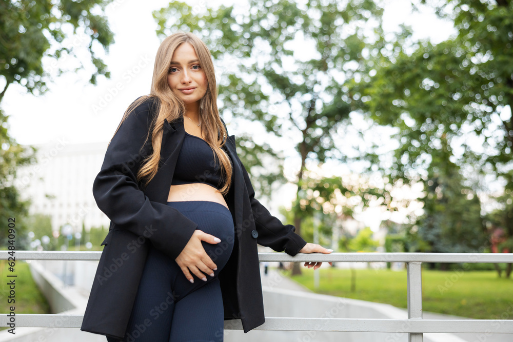 Pregnant woman is walking in a park outdoors. Pregnant mother spending time in the park Pregnant woman is walking in a park outdoors. Pregnant mother spending time in the park