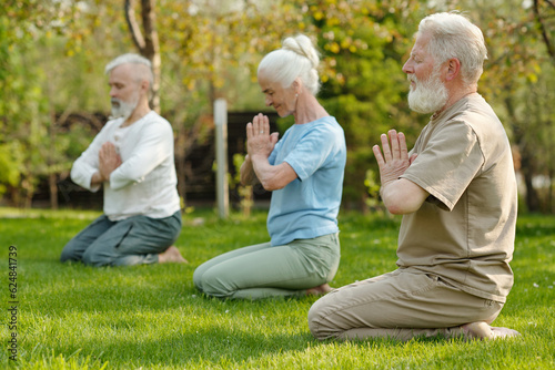 Focus on bearded senior man keeping hands put together by chest while practicing yoga exercise with other patients of retirement home © pressmaster