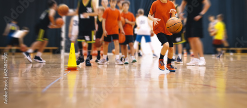 Children on basketball training. Group of school boys practicing basketball with a young coach. Kids play sports during a basketball training drills on a wooden court