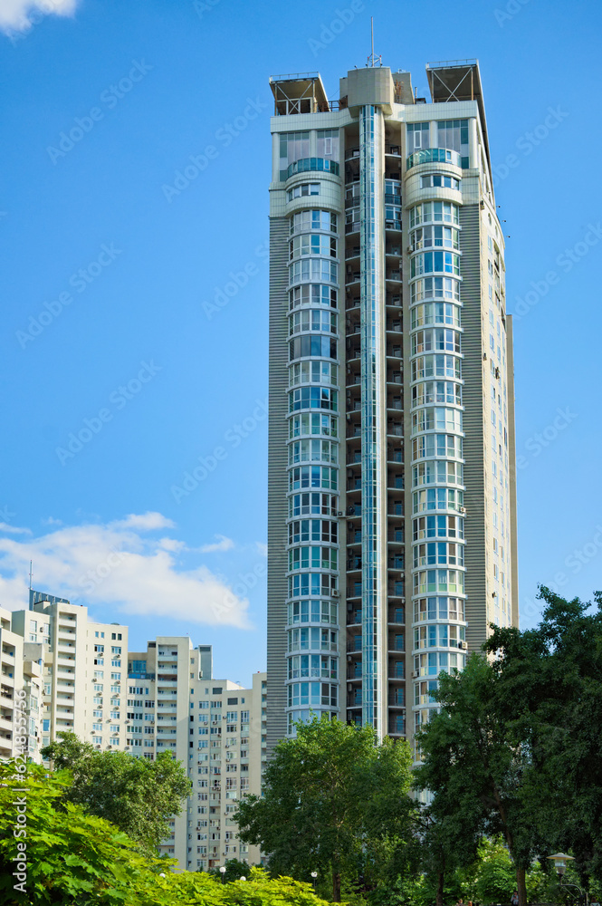 Obraz premium Low-angle view of modern high rise residential building. Blue sky with white clouds in the background. Modern architecture from glass and steel. Concept of real estate in Kyiv, Obolon neighborhood