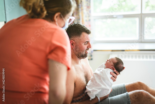 New born baby boy resting in father arms with nurse