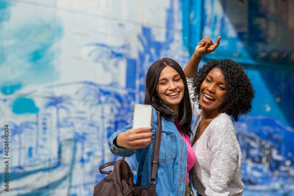 two cheerful female friends taking selfie with camera phone