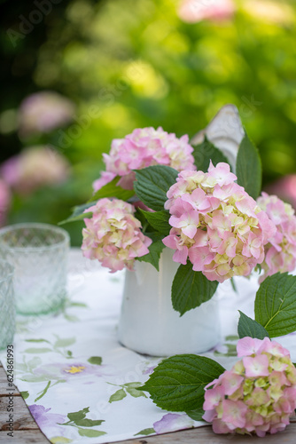 Fototapeta Naklejka Na Ścianę i Meble -  Tavolo decorato con un vaso di latta con fiori di ortensia di colore rosa