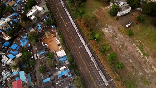 Follow drone footage of Mumbai local railway train moving to downtown Mumbai. Urban train aerial video. Indian commuter train in city. Topdown view of railway train in India