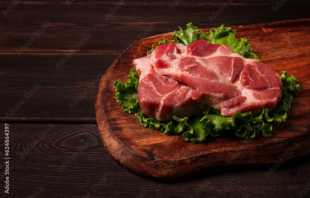 raw pork steak, two pieces, on a wooden background,