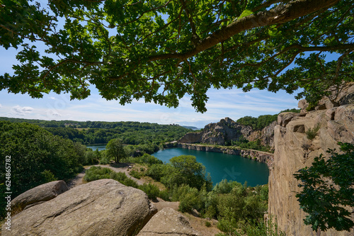 Blick auf den von Granitfelsen umgebenen künstlichen dunkelgrün-blauen See Opalsøen im Norden der dänischen Ostseeinsel Bornholm an einem Sommertag
