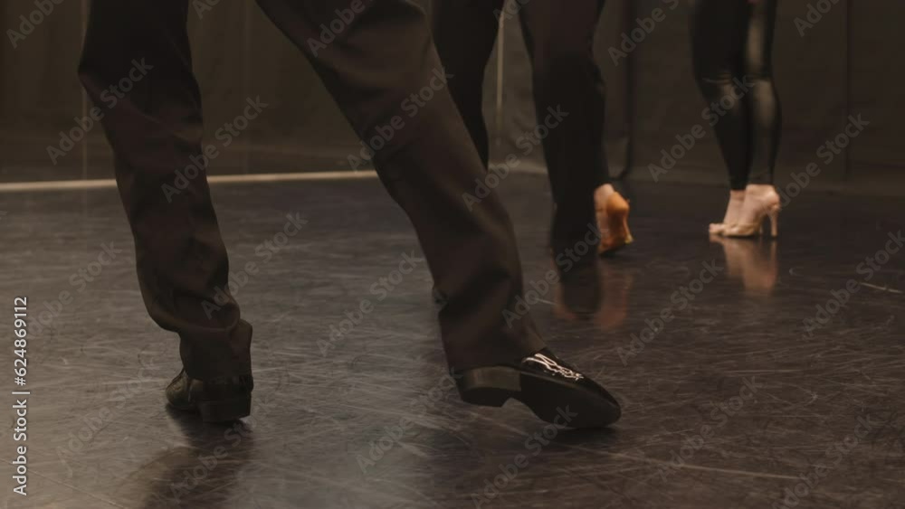 Low section slowmo of legs of unrecognizable men and women ballroom dancing in spacious dance studio with glossy parquet floor Low section slowmo of legs of unrecognizable men and women ballroom dancing in spacious dance studio with glossy parquet floor