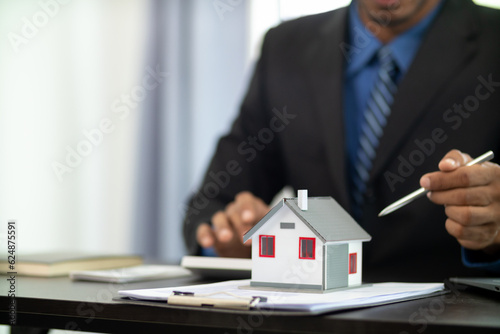 The real estate agent is reviewing the documents and calculating the interest rate to inform the tenant of the monthly installments to be paid before the real estate purchase agreement is finalized. photo