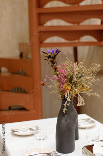 Beautiful flowers decorated on luxury elegant table setting dinner in a restaurant with wooden spiral staircase in soft focus