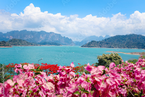 Beautiful point view of Ratchaprapa Dam or Cheow Lan Dam, crystal clear blue freshwater lake with mountains and cloudy sky as background, popular tourist attractions in Surat Thani province, Thailand.