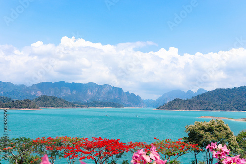 Beautiful point view of Ratchaprapa Dam or Cheow Lan Dam, crystal clear blue freshwater lake with mountains and cloudy sky as background, popular tourist attractions in Surat Thani province, Thailand. photo