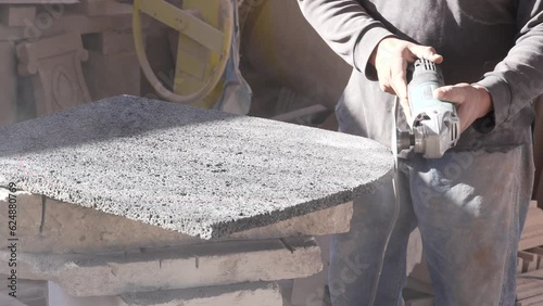 manual cutting with shackle, on enclosure, natural volcanic stone big man working