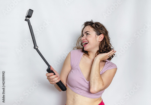 Cheerful woman taking a selfie. Black curly hair, lilac top.