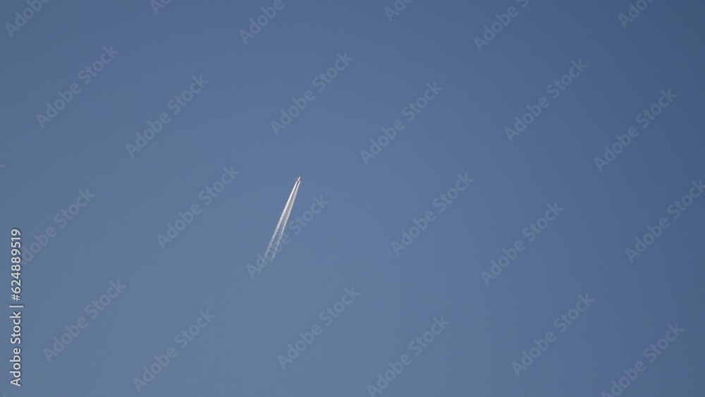 Contrail from a flying passenger plane against a blue sky at sunset. Condensation trails or vapor trails are line-shaped clouds produced by aircraft engine exhaust. Rovinj, Croatia - April 6, 2023 Contrail from a flying passenger plane against a blue sky at sunset. Condensation trails or vapor trails are line-shaped clouds produced by aircraft engine exhaust. Rovinj, Croatia - April 6, 2023