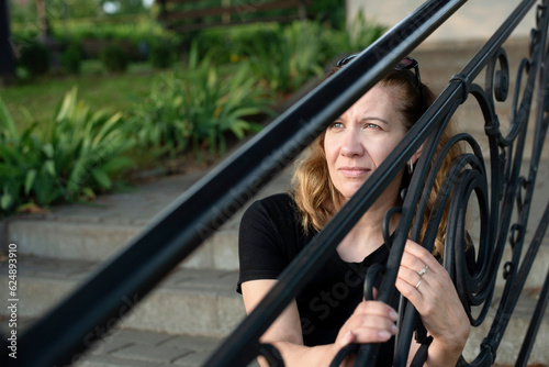 A woman sits on steps of church and looks hopefully at the sky, the woman is afraid to enter church, she thinks that God will not forgive her, but He loves her. The concept of forgiveness