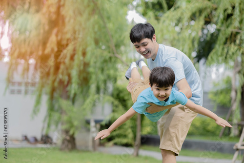 Young Asian father lift his son up playing like a plane wth smile of happiness, child enjoy playing with hisfather, relationship between dad and son.