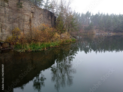 Picturesque aerial view of landscape with emerald lake and rocks in the middle of a coniferous autumn forest in Korostyshiv granite quarry, Zhytomyr district, northern Ukraine. Zhytomyr canyon photo