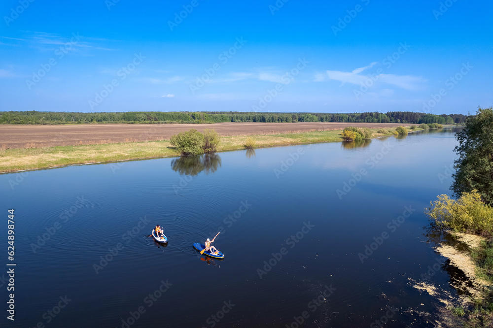 Funny man and woman floats on supboard on lake, sun light. Friends surfer on paddleboard. Concept summer active sport on water Funny man and woman floats on supboard on lake, sun light. Friends surfer on paddleboard. Concept summer active sport on water