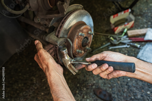 Car disk brake pad replacement service by hand of mechanic man. Auto mechanic repairing the breaks of a car