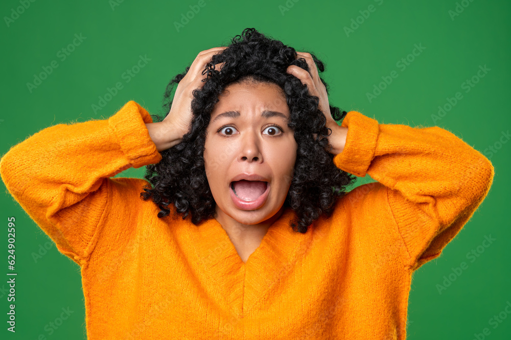 Dark-haired woman in orange looking stressed and shocked Dark-haired woman in orange looking stressed and shocked