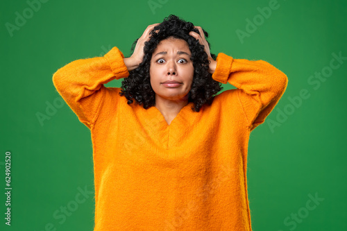 Dark-haired woman in orange looking stressed and shocked