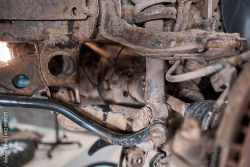 Car mechanic inspecting car wheel and repair suspension detail. Lifted automobile at repair service station. replacement of ferrule and leverage