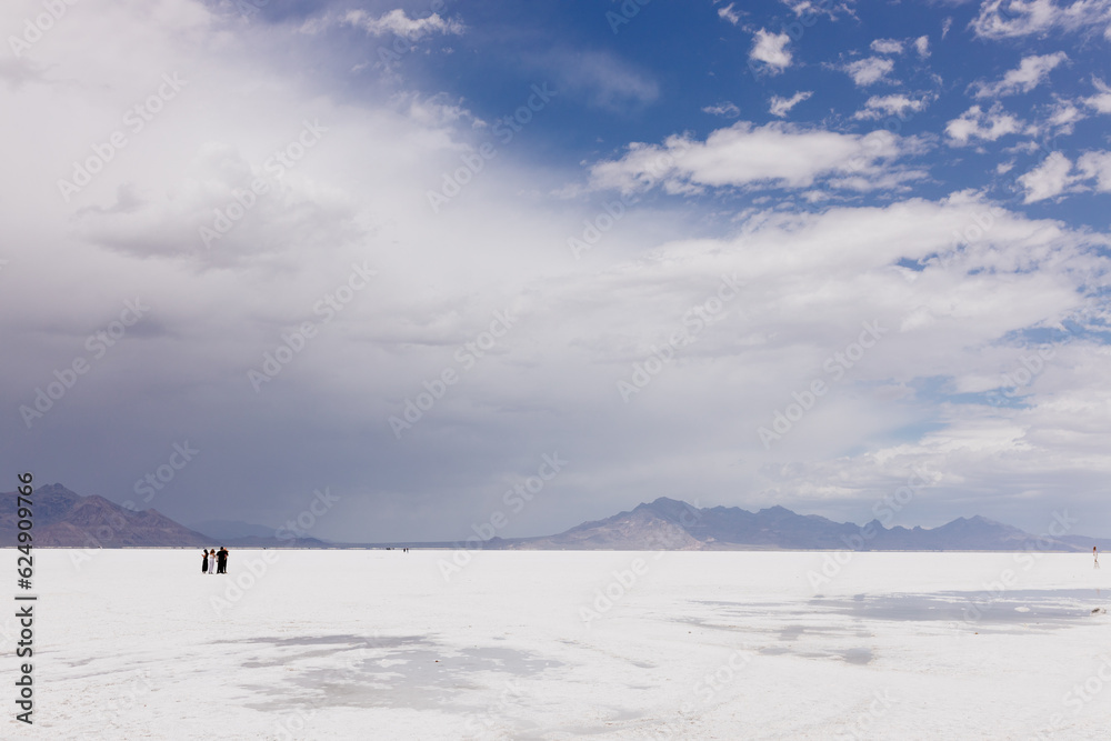 A beautiful unusual landscape on which a large desert of white salt and blue mountains in the distance on cloudy day. Bonneville Salt Flats, Utah, USA - 19 June 2023
