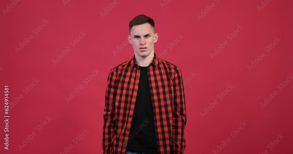 A dissatisfied man is depicted against a striking red backdrop. With a stern expression on his face, he firmly lowers both thumbs down, indicating a negative response or disapproval. A dissatisfied man is depicted against a striking red backdrop. With a stern expression on his face, he firmly lowers both thumbs down, indicating a negative response or disapproval.