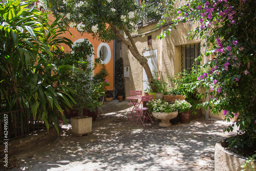 Mediterranean garden design and landscaping,Provence,France: Cozy patio with natural stone paving, a resting place beautifully planted with bougainvillea, oleander and green plants in a small village 