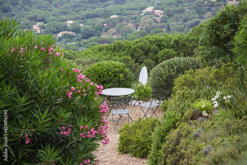 Mediterranean garden design and landscaping, Provence, France: Beautiful resting place - two metal chairs and a round table surrounded by oleander and green plants with view to a hill with pine trees